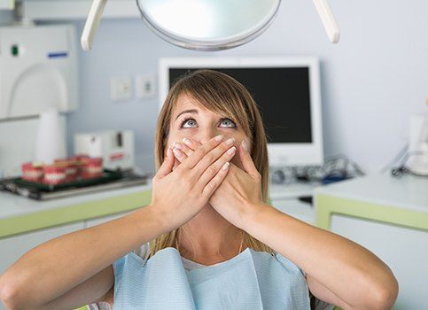 Woman at dental office for root canal covering her mouth