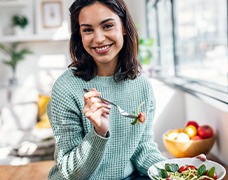 Woman smiling while eating healthy meal at home