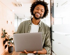 Smiling man holding laptop in office