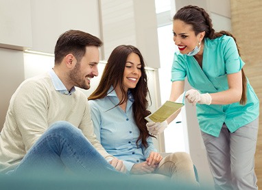 Dental assistant showing smiling couple form