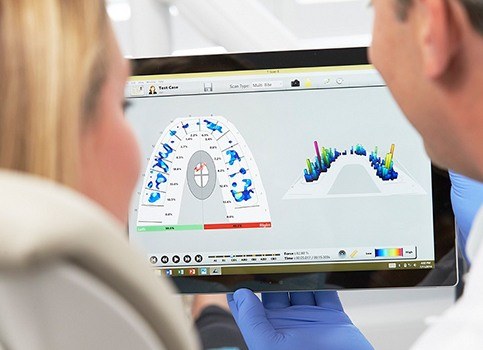 Dentist and patient looking at cavity detection system report