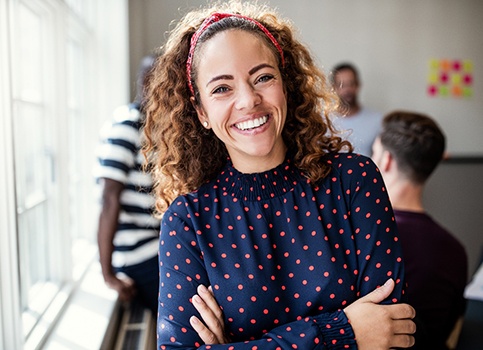 A young female at work smiling and pleased with the dental crown she received