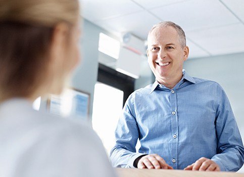 Man checking in at dental office reception desk