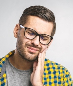 Man in need of emergency dentistry holding cheek