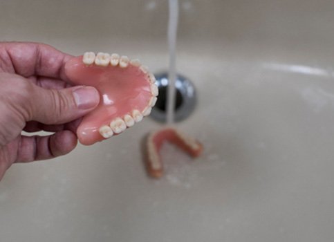 Dentures being rinsed in a sink
