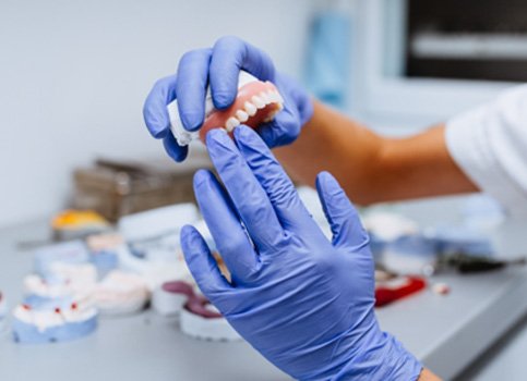 A worker closely examining a denture