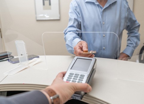 An adult man paying the cost of dentures