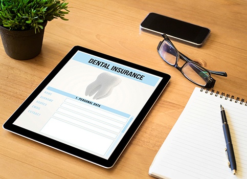 Dental insurance form on tablet next to desk supplies