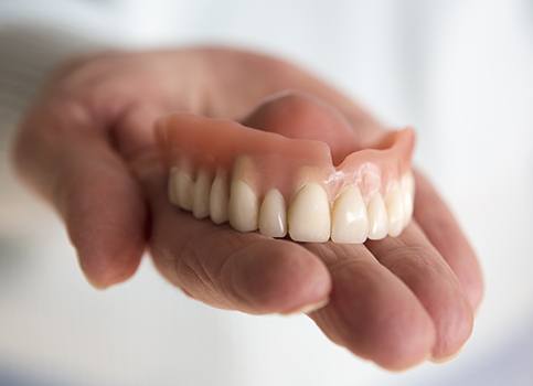 Hand holding full denture