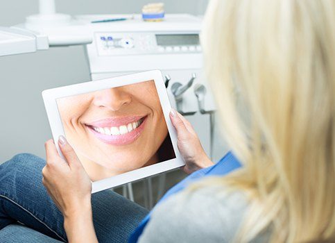 Woman looking at virtual smile design on tablet computer