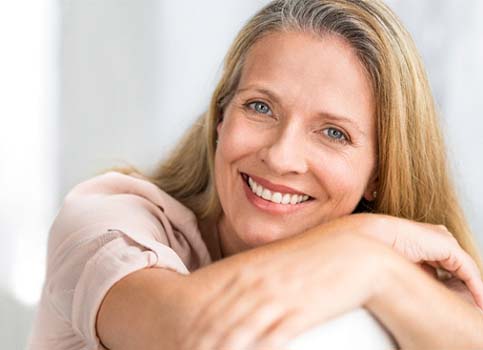 Older woman in pink shirt crossing her arms over chair