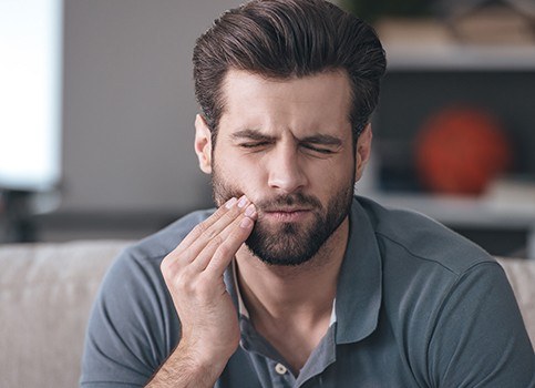 Man in need of tooth extraction holding jaw