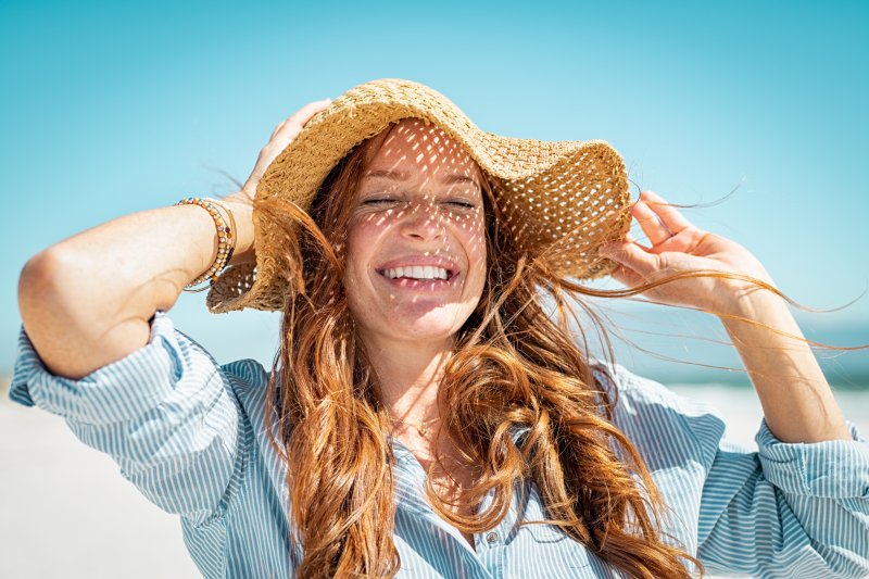 Woman in straw hat smiling by the ocean