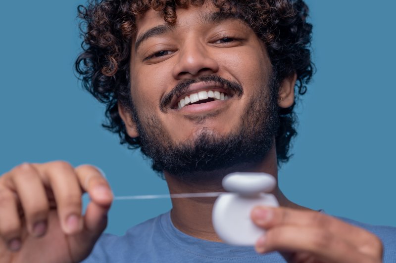 man smiling and getting ready to floss