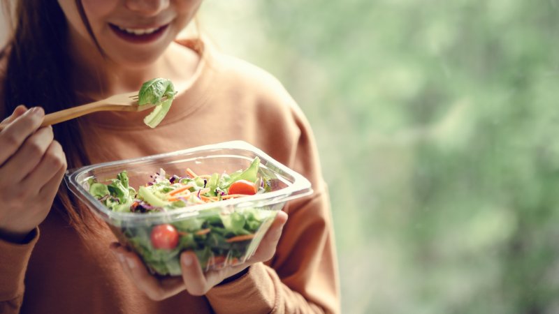 Smiling woman eating salad