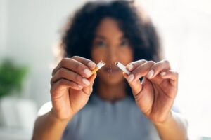 Woman breaking cigarette in half.